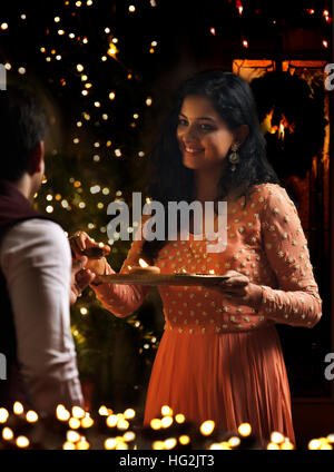 Junge paar hält Öl Lampen in eine Platte auf diwali Stockfoto