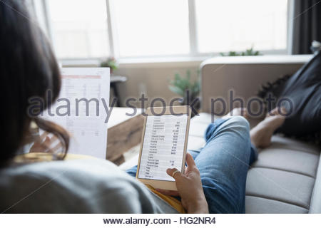 Junge Frau, die Überprüfung der persönlicher Finanzen mit digital-Tablette und Papierkram auf sofa