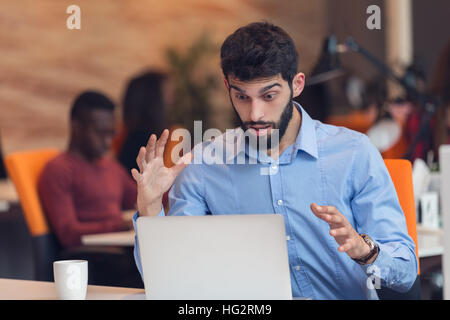 frustrierte junge Geschäftsmann auf Desktop-Computer arbeiten Stockfoto