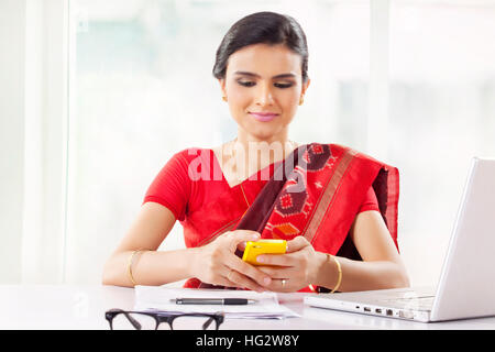 Indische Frau, die im Büro mit Handy Stockfoto