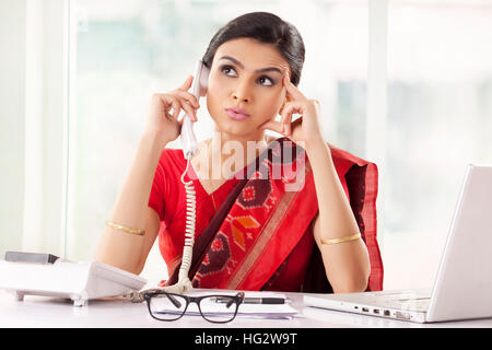 Attraktive indische Rezeptionist sprechen über das Telefon Stockfoto