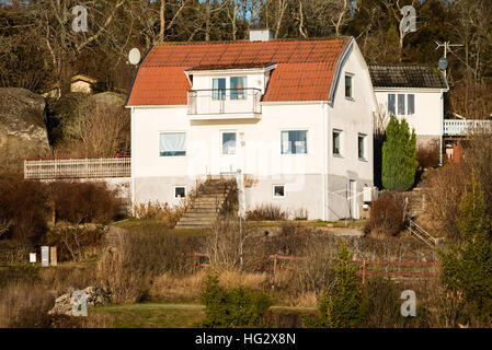 Ronneby, Schweden - 2. Januar 2017: Dokumentation der ländlichen Lebensstil. Typisch schwedische Hügel mit Wald im Hintergrund nach Hause. Etwas wilden Garten. Stockfoto