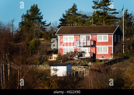 Ronneby, Schweden - 2. Januar 2017: Dokumentation der schwedische Landleben. Rotes Holzhaus auf einem Hügel mit den umliegenden Wald. Stockfoto