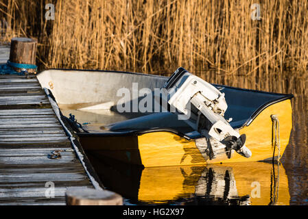 Gelbe Motorboot in hölzerne Pier festgemacht an kalten und frostigen Morgen. Boot ist voll von Eiswasser. Motor aus dem Meer gehoben. Stockfoto