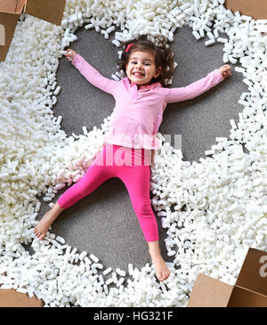 Kind macht Schneeengel mit Schaum Verpackung Stockfoto