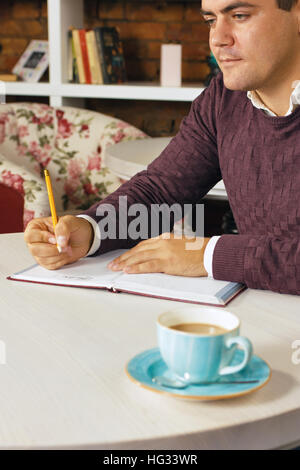 Mann hält Bleistift und schreiben auf dem Papier im Tagebuch Stockfoto