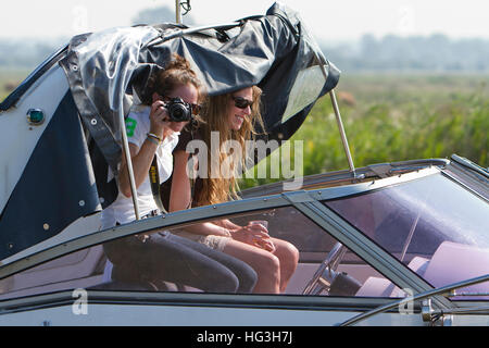 Mädchen nehmen Foto mit Nikon-Kamera von vorbeifahrenden Kreuzer auf Norfolk Broads Stockfoto