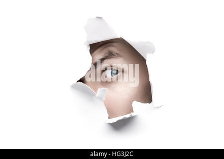 Mann auf der Suche durch weiße Papier Loch gerissen Stockfoto