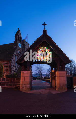 Bunte, funkelnden, beleuchtete, Adventskranz in einer Winternacht - Lynch-Tor, St. Johann Kirche, Baildon, Yorkshire, England. Stockfoto