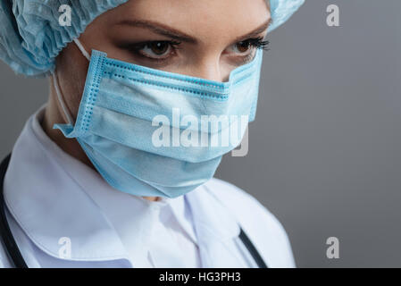 Schöne Frau, die trägt medizinische Gesichtsmaske Stockfoto