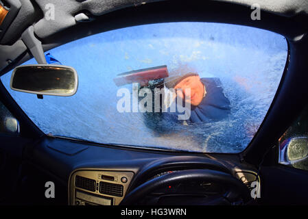 Mann mit Eiskratzer, klare Windschutzscheibe aus dickem Eis uk Stockfoto