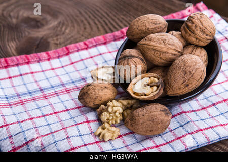 Walnuss-Kerne und ganze Walnüsse auf alten hölzernen Tisch und Teller-Handtuch Stockfoto