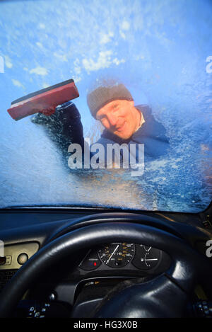 Mann mit Eiskratzer, klare Windschutzscheibe aus dickem Eis uk Stockfoto