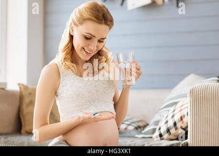 Schwangere Frau, die Einnahme von Pillen in ihrem Zimmer Stockfoto