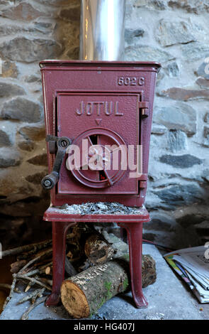 Alten Jotul 602C-Kaminofen mit geschlossener Tür Protokolle brennende Feuer Flammen in einer Steinhütte in Wales UK KATHY DEWITT Stockfoto