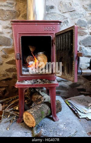 Alten Jotul 602C-Kaminofen mit Tür offene Protokolle brennende Feuer Flammen in einer Steinhütte in Wales UK KATHY DEWITT Stockfoto