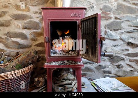 Alten Jotul 602C-Kaminofen mit Tür offene Protokolle brennende Feuer Flammen in einer Steinhütte in Wales UK KATHY DEWITT Stockfoto