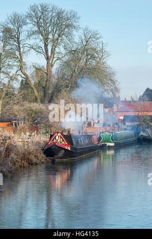 Kanalboot mit Rauchen Schornstein am Oxford-Kanal auf einem frostigen Dezembermorgen. Cropredy, Oxfordshire, England Stockfoto