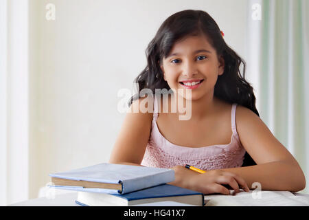 Portrait von lächelnden cute girl am Schreibtisch mit Bücher Stockfoto