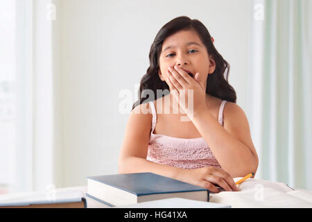Mädchen Gähnen während Hausaufgaben Stockfoto