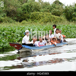 Kleines Boot mit Schulkindern entwässert schwimmende Dorf der Sangkhae - Sangker River Battambang Provinz Cambodia.The Tonle Sap See (reichsten See zum Angeln in der Welt) in den Mekong-Fluss in Phnom Penh. Die kambodschanische Bevölkerung hat auch für das einzigartige Ökosystem des Sees mit schwimmenden angepasst (Fischer-Fischerei) Dörfer und gestelzt Häuser. Stockfoto