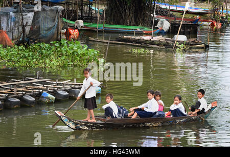 Kleines Boot mit Schulkindern entwässert schwimmende Dorf der Sangkhae - Sangker River Battambang Provinz Cambodia.The Tonle Sap See (reichsten See zum Angeln in der Welt) in den Mekong-Fluss in Phnom Penh. Die kambodschanische Bevölkerung hat auch für das einzigartige Ökosystem des Sees mit schwimmenden angepasst (Fischer-Fischerei) Dörfer und gestelzt Häuser. Stockfoto