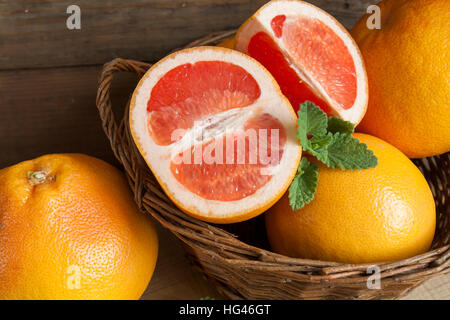 Frisch geerntete Grapefruit im Korb auf dunklem Holz Stockfoto