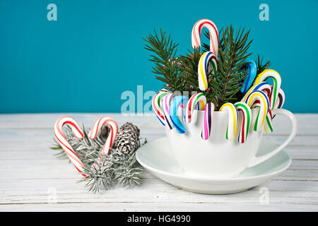 Christmas candy Canes und Kiefer in weißen Kaffeetasse mit Herz auf weiß getünchten Holz Stockfoto