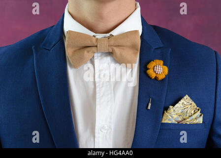 Mann in blau Anzug mit braunen Fliege, Blumenbrosche und klassischen Textur Tasche Platz, in der Nähe Stockfoto