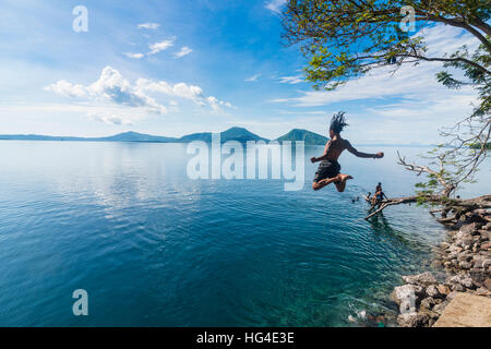 Mann springt in die Bucht von Rabaul mit Vulkan Tavurvur im Hintergrund, East New Britain, Papua-Neuguinea, Pazifik Stockfoto