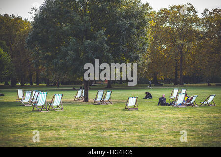 Leute sitzen auf dem Rasen entspannen im Green Park in London in der Nähe von der Lounge chair Stockfoto