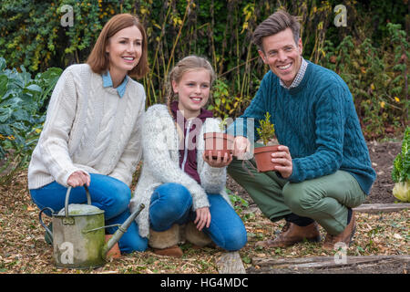 Attraktive, erfolgreiche und glückliche Familie, Mann, Frau, Mädchen, Mutter, Vater und Tochter zusammen im Garten Gemüsebeet Gartenarbeit Stockfoto