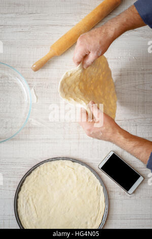 Mann Kochen Teig für zwei Pizzen auf den Tisch, die vertikale Stockfoto