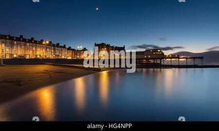 Aberystwyth promenade Gebäude und Pier am frühen Abend. Ein Halbmond und dem Planeten Venus auch abgebildet. Ceredigion, Wales, UK Stockfoto