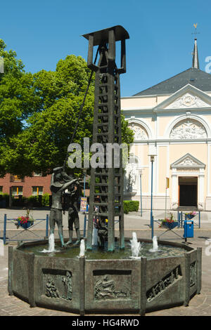 Deutschland, NRW, Städteregion Aachen, Herzogenrath-Kohlscheid, Bergarbeiterbrunnen vor der katholischen Kirche Sankt Katharina Stockfoto