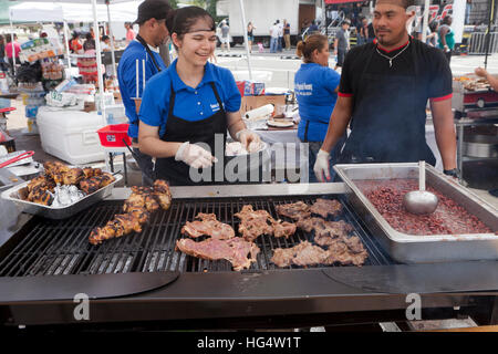 Latino-Frau kochen Fleisch am Grill Kühlergrill auf ein outdoor-Event - USA Stockfoto