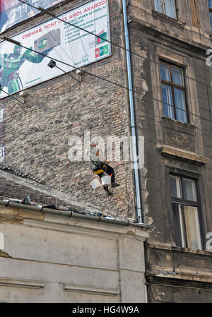 Unbekannte Industriekletterer Arbeitnehmer hängt an Seilen renovieren, die Fassade der alten Gebäude in der Innenstadt von Budapest. Stockfoto