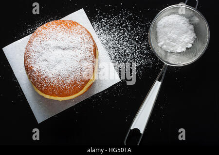 Donut und Puderzucker auf dunklem Hintergrund Stockfoto