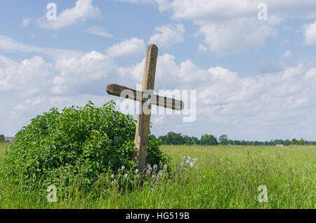 alten verwitterten hölzernen katholische Kreuz auf der grünen Wiese Stockfoto