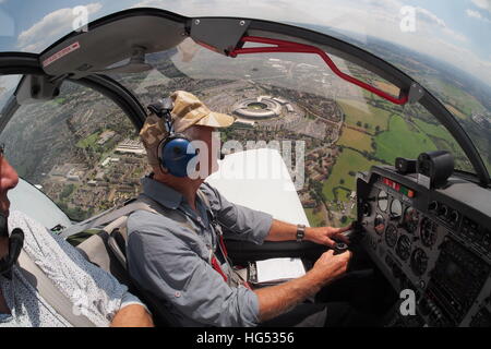 fliegt ein Flugzeug in der Nähe von Cheltenham Gloucestershire UK mit GCHQ im Hintergrund Stockfoto