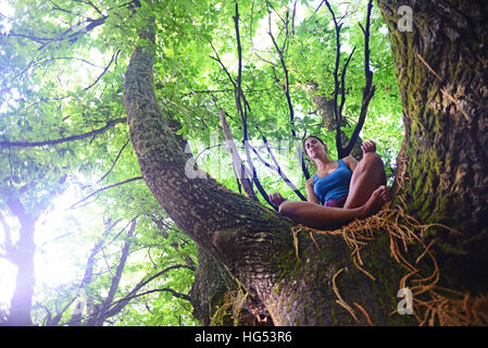 Junge Frau meditiert über großen Kastanienbaum. Stockfoto