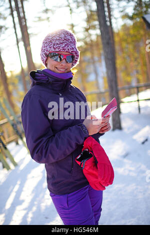 Junge attraktive Frau mit Mobiltelefon im Skigebiet Jugendpfleger, Lappland Stockfoto