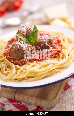 Ein Teller mit Spaghetti mit Fleischbällchen, garniert mit geriebenem Parmesan und Basilikum. Stockfoto