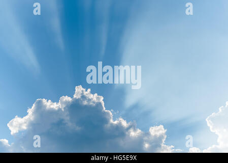 Sonnenstrahlen, die durch Wolken am blauen Himmel Stockfoto