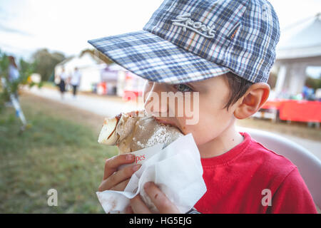 Junge mit einer Kappe einen Pfannkuchen essen Stockfoto