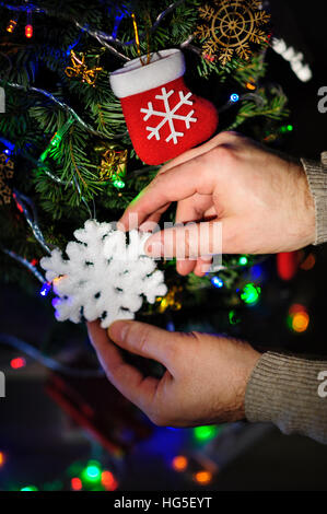 Man schmückt einen Weihnachtsbaum mit Spielzeug Stockfoto