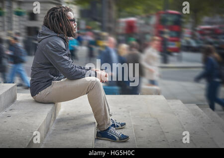 schwarzer Mann.  Mann zu betrachten.   Dreadlocks.  Rastafari.   Allein in der Stadt. Stockfoto