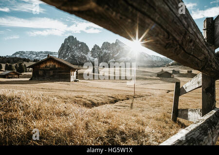 Holzhäuser auf einem Feld am Fuße einer Bergkette. Stockfoto