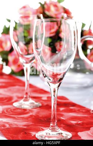 Tisch mit Weingläsern, Strauß Rosen im Hintergrund Stockfoto