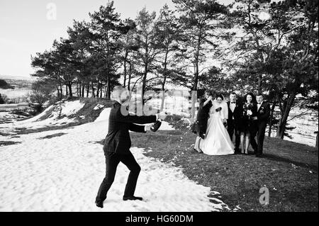 Trauzeuge mit Brautjungfern und Brautpaar trinken Champagner auf Frost-Winter-Hochzeit. Schwarz / weiß Foto Stockfoto